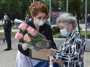 Юлия Владимировна Рокотянская вручает благодарственное письмо, цветы и подарок Антонине Андреевне Булатниковой